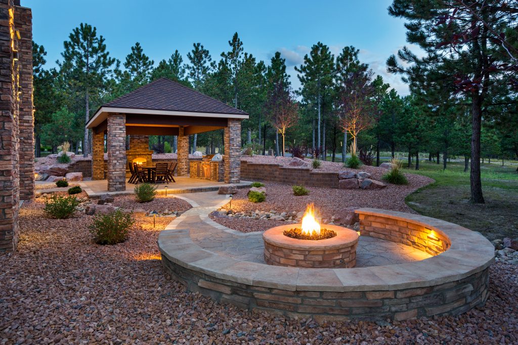 Outdoor cement patio with brick columns and stone fireplace with stamped concrete